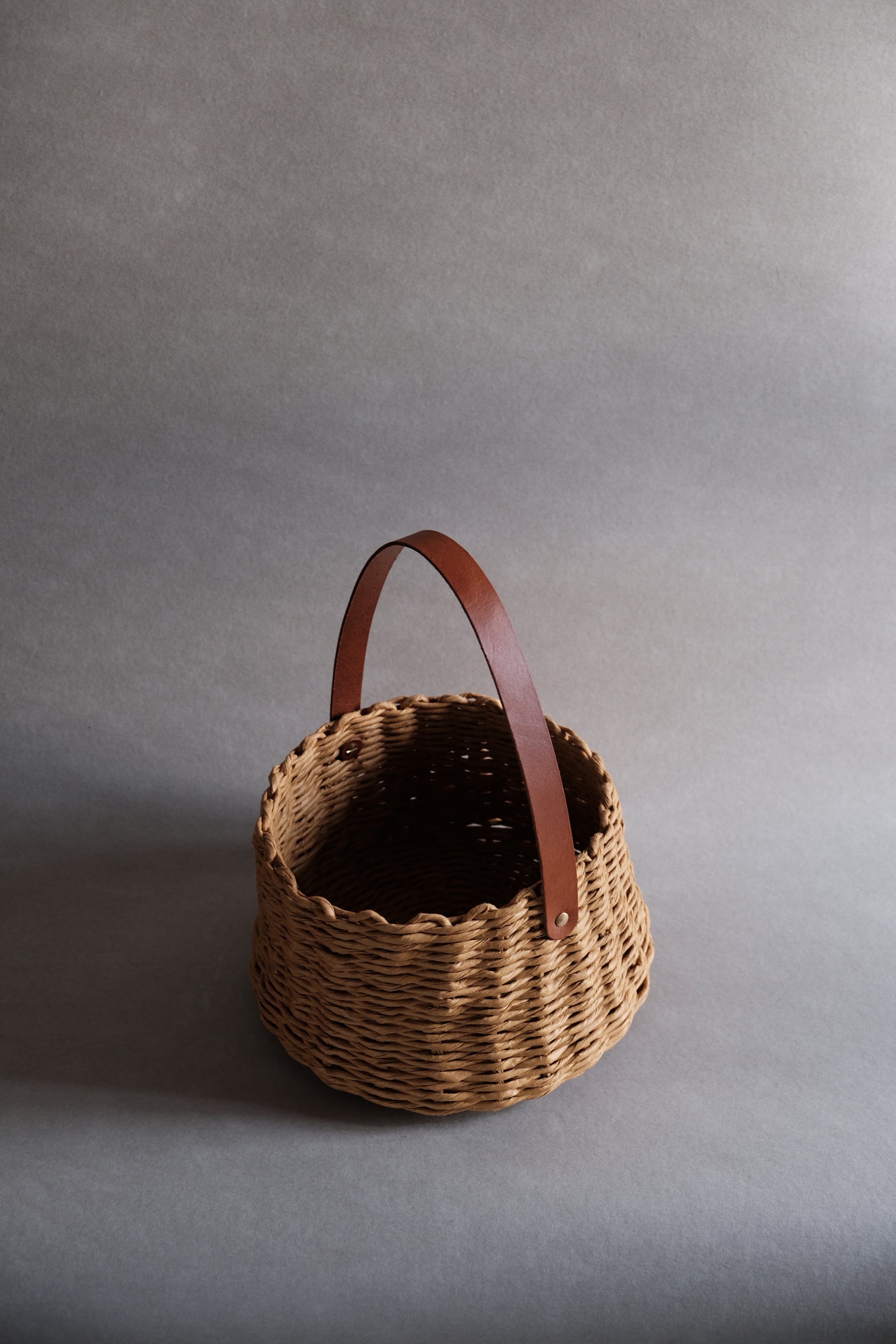 フランス製紙撚り糸をデザイナーが手編みしたCOCOON BASKET（コクーン バスケット）。丸みのある繭のようなフォルムと、真鍮金具で固定されたレザーハンドルが美しい、オーストリア製ハンドメイドのカゴバッグ。