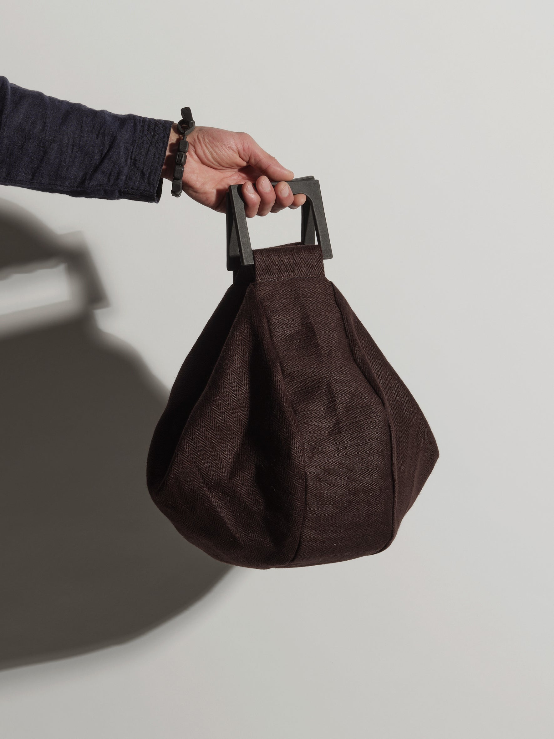 Langackerhäuslのしずく型リネンバッグDROP（ドロップ）。ヘリンボーンリネンに独自の「Tor」紙製グリップハンドルを組み合わせた、前面の垂直ファスナーが特徴のオーストリア製ハンドメイド手提げバッグ。