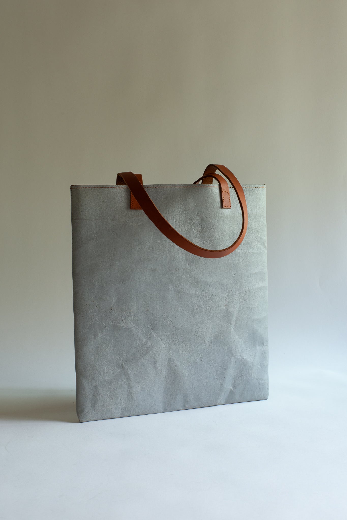 LangackerhäuslのコンクリートトートバッグSLEEVE（スリーブ）。コンクリートの質感と紙の柔軟性を併せ持つ独創的な素材を使用し、長いレザーハンドルがアクセントを添えるオーストリア製ハンドメイド縦型トート。