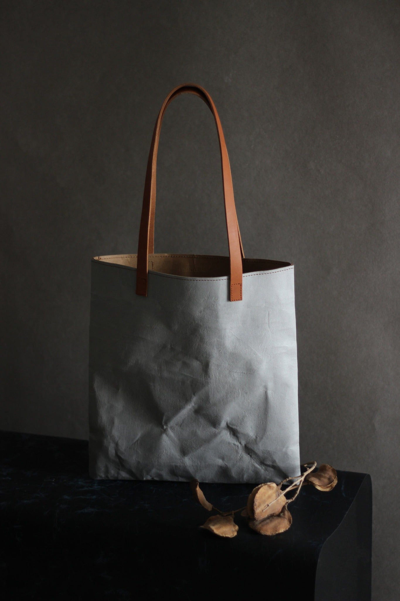 LangackerhäuslのコンクリートトートバッグSLEEVE（スリーブ）。コンクリートの質感と紙の柔軟性を併せ持つ独創的な素材を使用し、長いレザーハンドルがアクセントを添えるオーストリア製ハンドメイド縦型トート。
